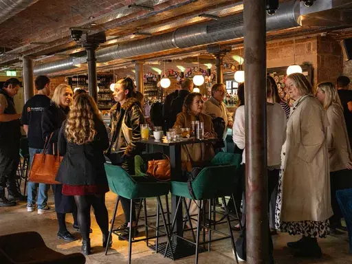 Attendees mingling around high tables in an exposed-brick venue at a Darlington First coffee morning.