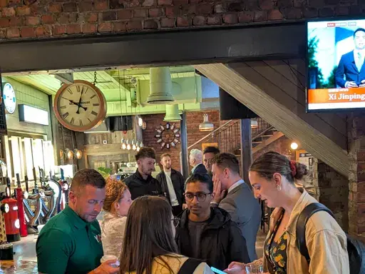 Groups of attendees deep in conversation by the bar at a Newcastle First coffee morning.