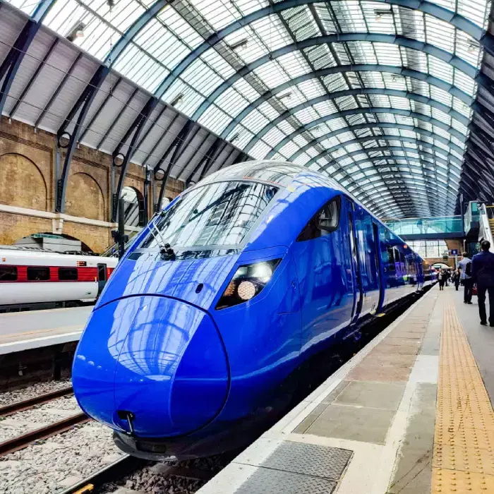 A blue Lumo train waiting at the platform under the arched glass roof of London King’s Cross.